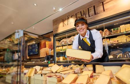 Verkäuferin an Käse Theke hält einen Leib Käse